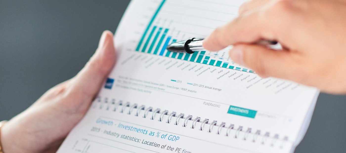 Manos señalando gráficos de un informe económico impreso